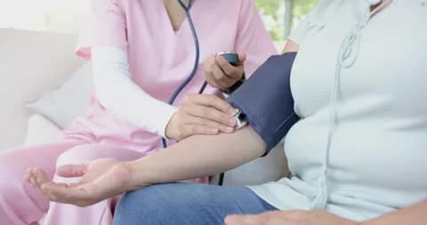 Nurse taking blood pressure at home